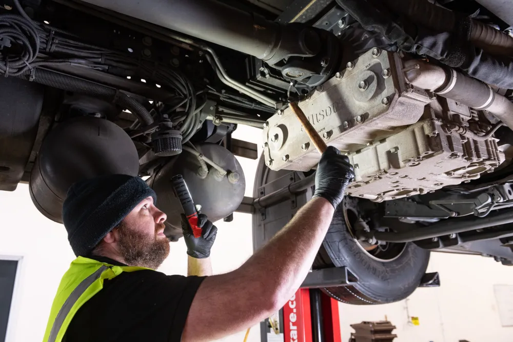 A fitter inspects a raised vehicle