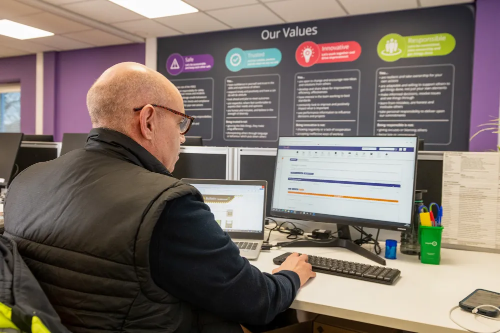 A worker in the office facing a wall that displays CWR values