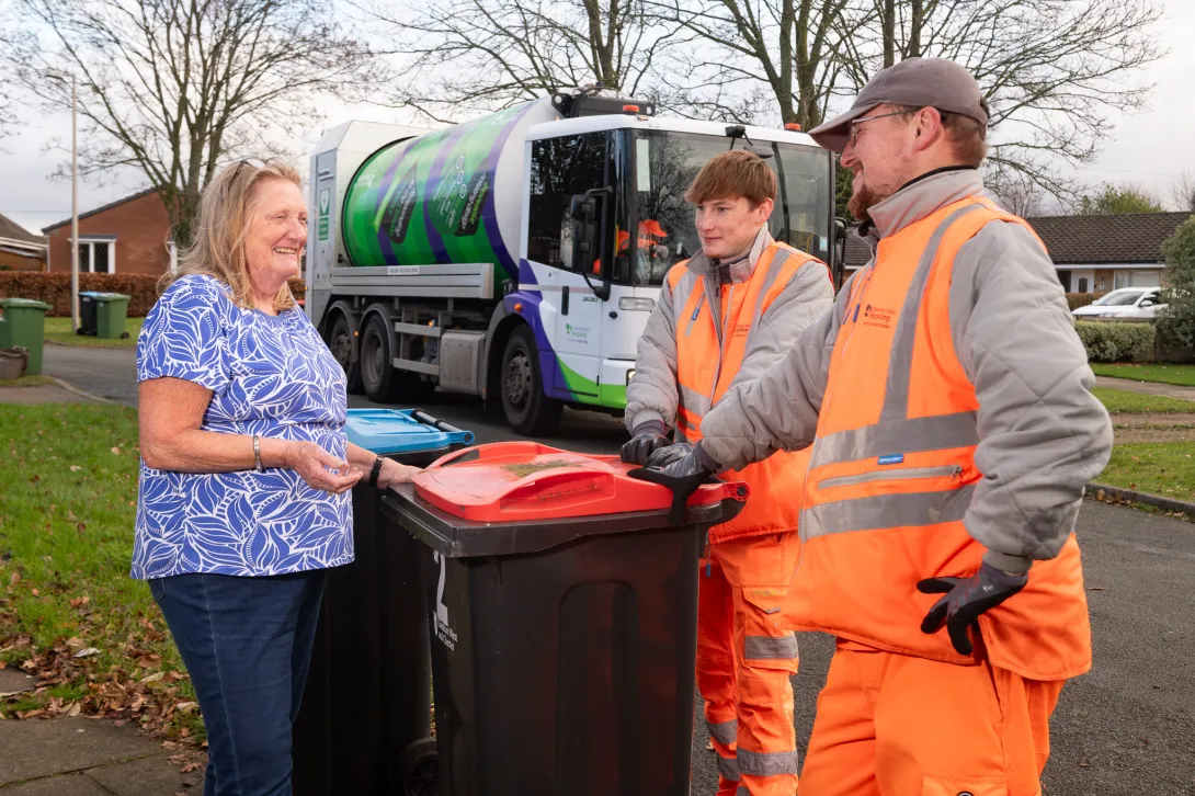 A resident speaks to two loaders during recycling collection